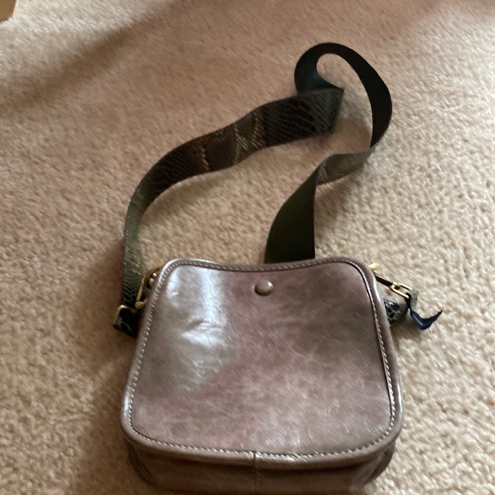 It is a over the shoulder gray bag with snake print
